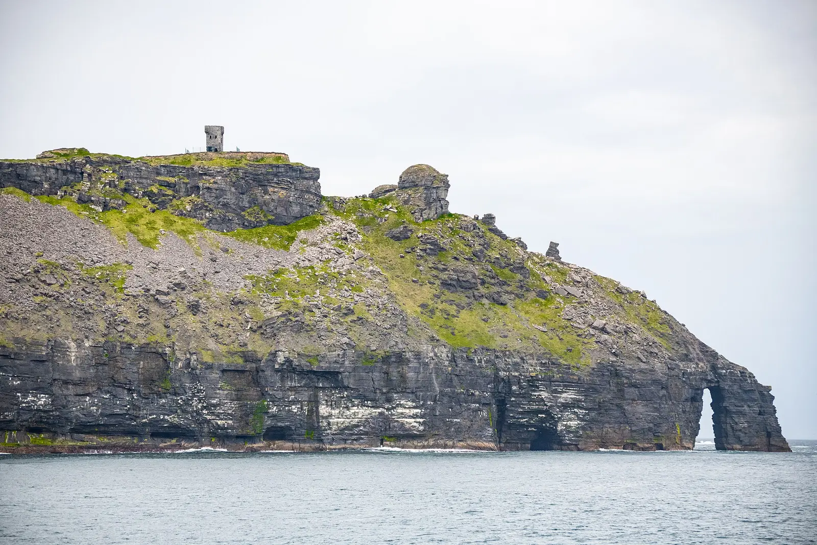 Hag's Head and Moher Tower seen from a boat, with a sea arch at the waterline